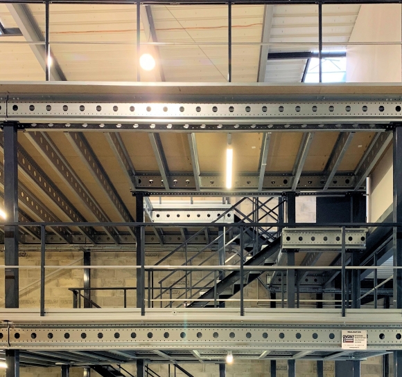 Double metal staircases provide access to several levels of a platform in a warehouse]
		                    